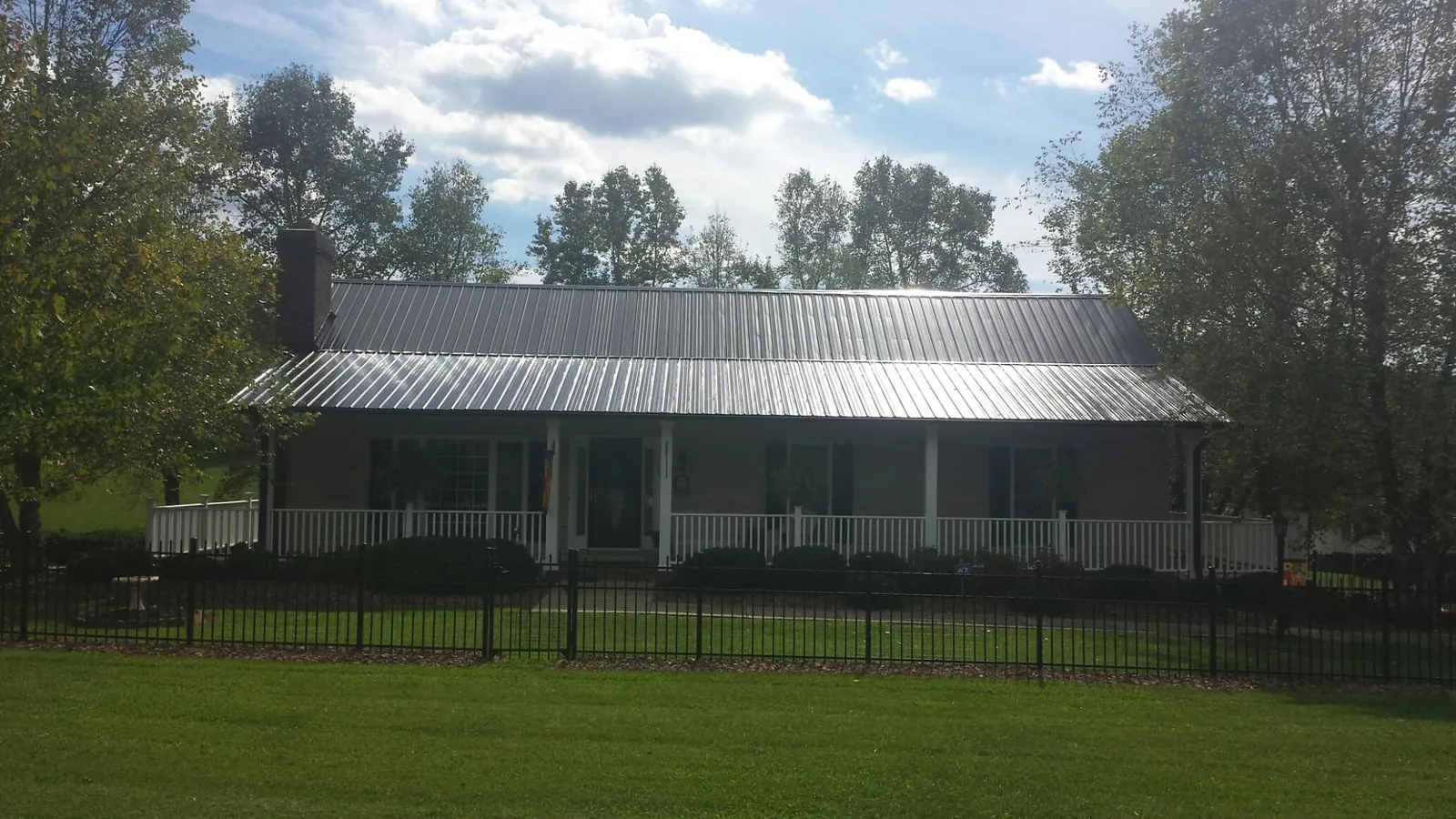 Gray metal roof on a brick ranch with a full width front porch — Gutter Guard Installation work by our crew in Wiggins