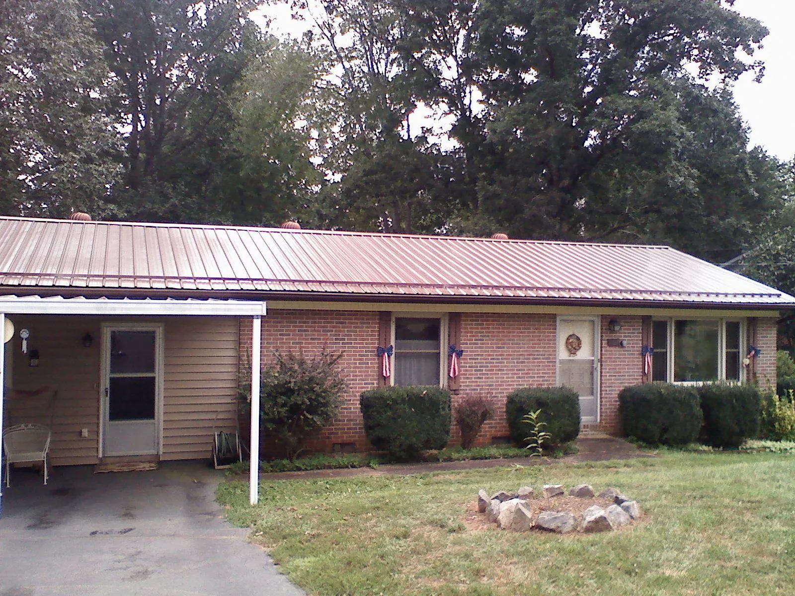 Bronze metal roof and carport on a brick ranch home — Roof Repair work by our crew in Wiggins